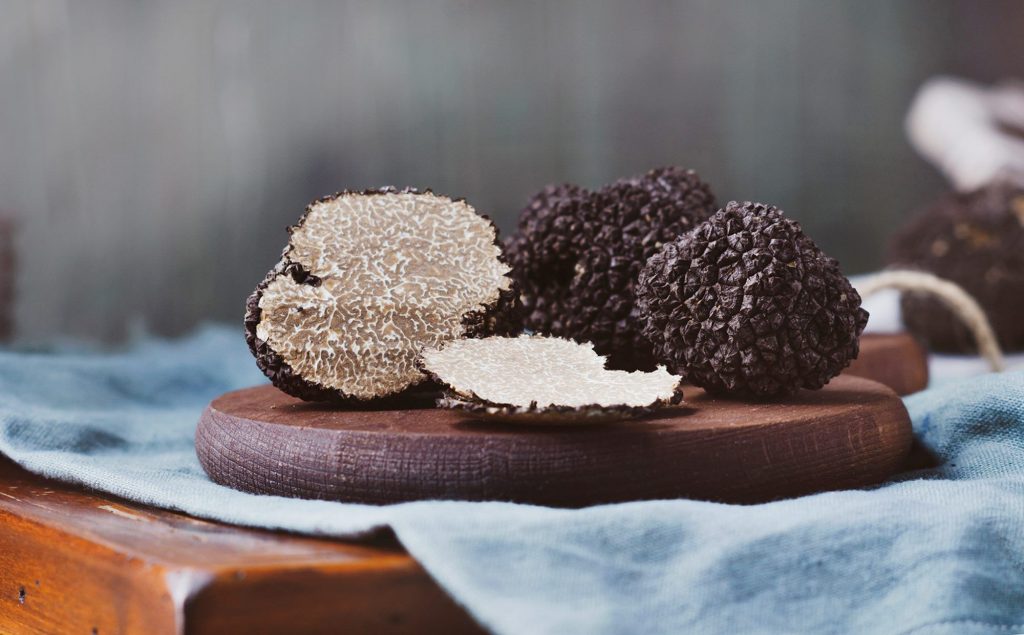 Truffes noires entières et tranchées sur une planche en bois